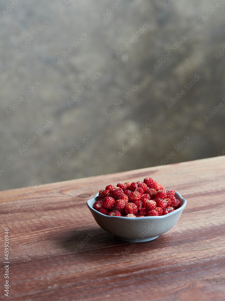 fresh wild strawberries in a small bowl on a wooden table. fragaria vesca fresh wild strawberries in a small bowl on a wooden table. fragaria vesca
