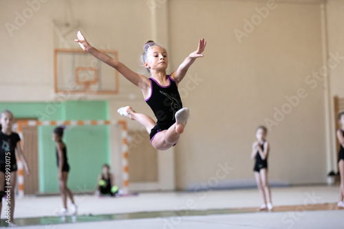 Fototapeta Naklejka Na Ścianę i Meble -  Girl gymnast jumping the splits on training in gym