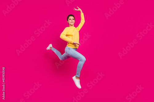 Photo of cute funny young woman dressed yellow pullover jumping dancing smiling isolated pink color background