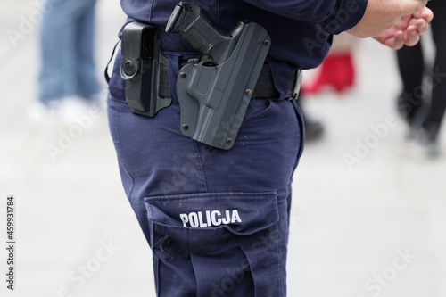 Polscy policjanci w niebieskim mundurze na zabezpieczeniu imprezy w mieście z wyposażeniem służbowym. 