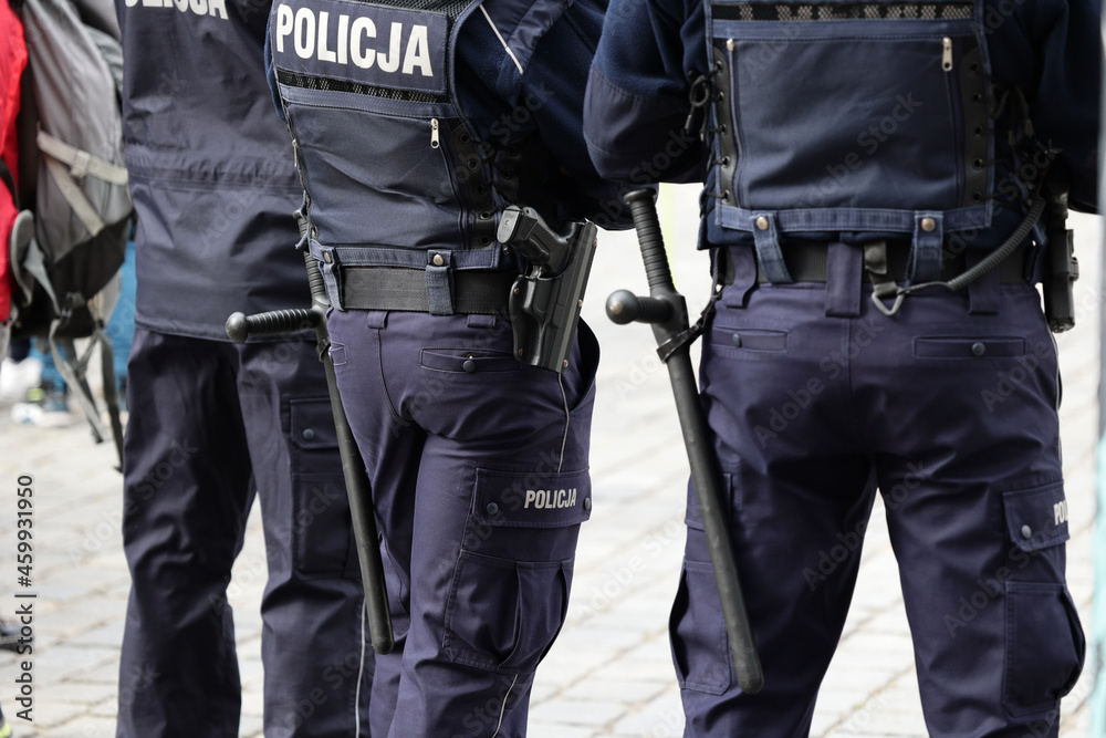 Polscy policjanci w niebieskim mundurze na zabezpieczeniu imprezy w mieście z wyposażeniem służbowym.  - obrazy, fototapety, plakaty 