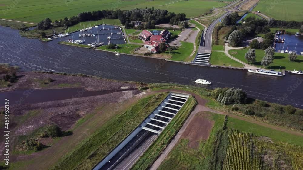 Aquaduct structure connecting a lake over a highway like a water-bridge, boat sailing on the canal and cars driving under it Aquaduct structure connecting a lake over a highway like a water-bridge, boat sailing on the canal and cars driving under it