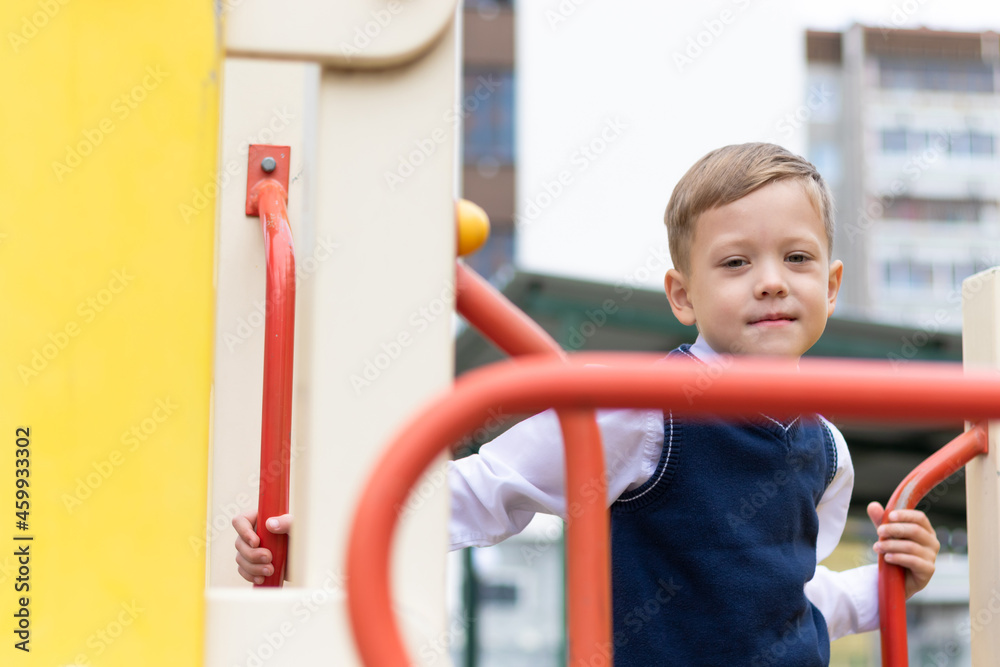 Cute boy first grader at school on the playground on a sunny autumn day. Celebration on September 1st. Knowledge day. Selective focus Cute boy first grader at school on the playground on a sunny autumn day. Celebration on September 1st. Knowledge day. Selective focus