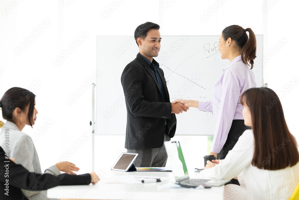 businesswoman and businessman shaking hands together with partners for a job in conference room businesswoman and businessman shaking hands together with partners for a job in conference room