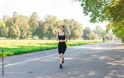 Athletic young happy woman runing in the park jogging in the morning for lifestyle health. Outdoor workout. Sport and healthy active lifestyle concept.