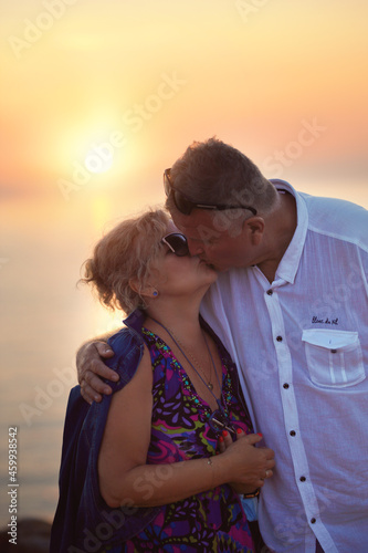 tender and romantic kiss of an elderly couple during the sunset