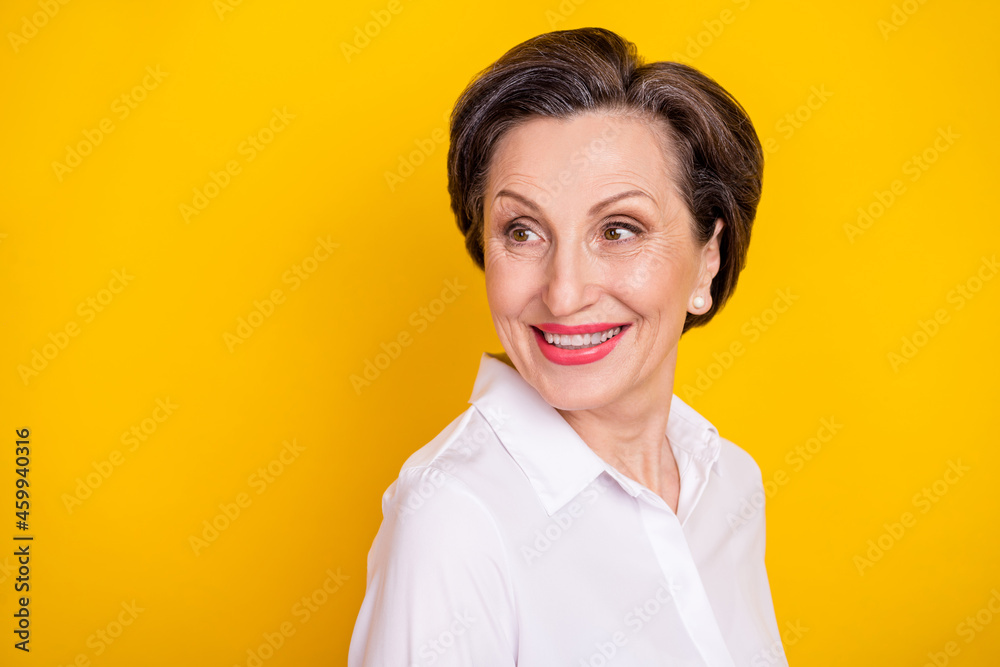 Photo of confident pretty age woman dressed white shirt smiling looking back empty space isolated yellow color background Photo of confident pretty age woman dressed white shirt smiling looking back empty space isolated yellow color background