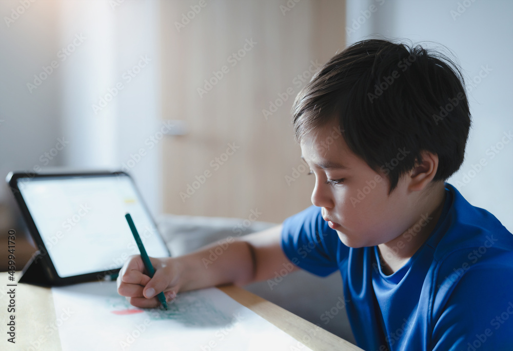 Portrait Schoolboy using colour pen drawing on white paper sheet, Young kid using tablet for school homework online on internet, Happy child enjoy painting. Home Education Portrait Schoolboy using colour pen drawing on white paper sheet, Young kid using tablet for school homework online on internet, Happy child enjoy painting. Home Education
