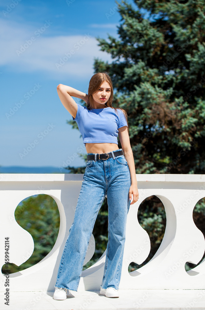 Young beautiful blonde girl in blue jeans, summer park outdoors