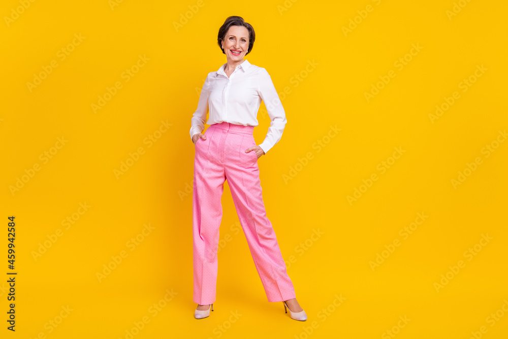Fototapeta premium Photo of sweet confident mature lady wear white clothes smiling standing arms pockets isolated yellow color background