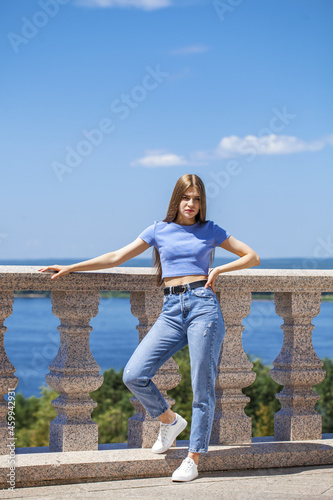 Full body portrait of a young beautiful blonde girl in blue jeans, summer park outdoor 