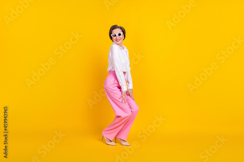 Full body profile side photo of aged woman happy positive smile wear sunglass isolated over yellow color background