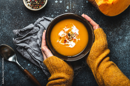 Female hands with bowl of pumpkin soup photo