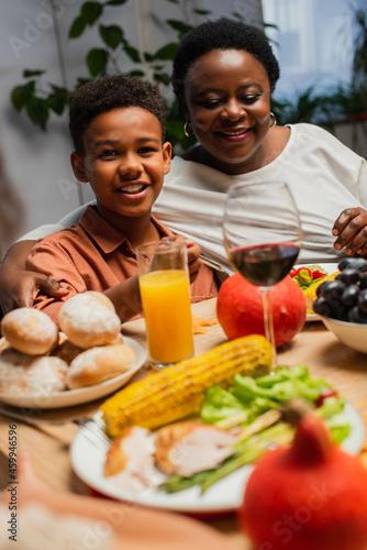 cheerful african american boy smiling near happy granny during thanksgiving dinner