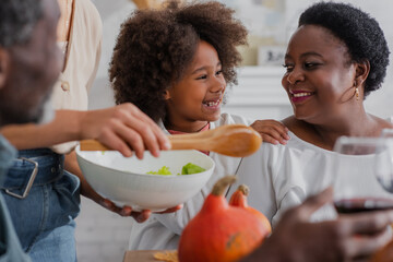 Smiling african american girl hugging grandmother during thanksgiving dinner