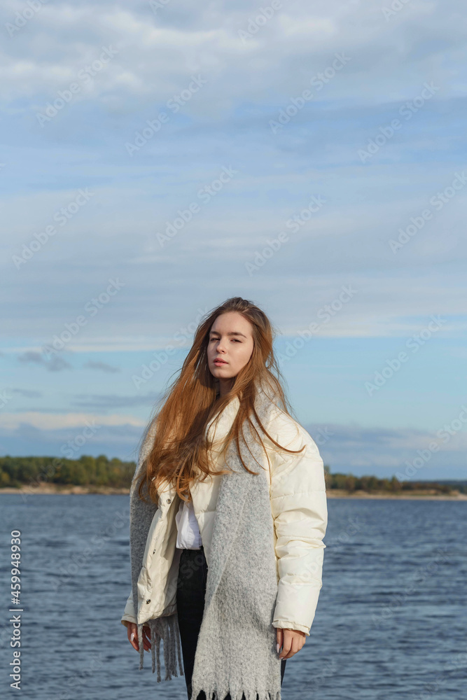 a girl in a light jacket and with a gray scarf on the bank of the Volga