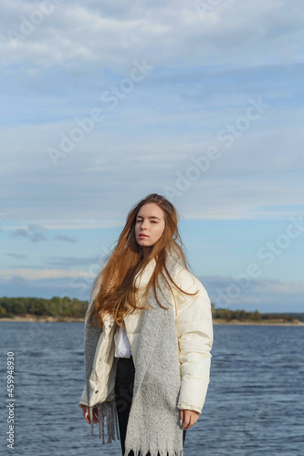 a girl in a light jacket and with a gray scarf on the bank of the Volga