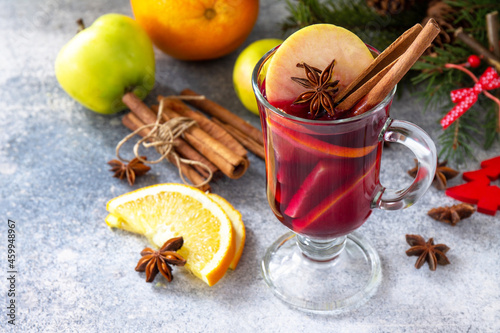 Christmas mulled wine, winter alcoholic drink. A glass of mulled wine (gluhwein) and its ingredients on a stone background.