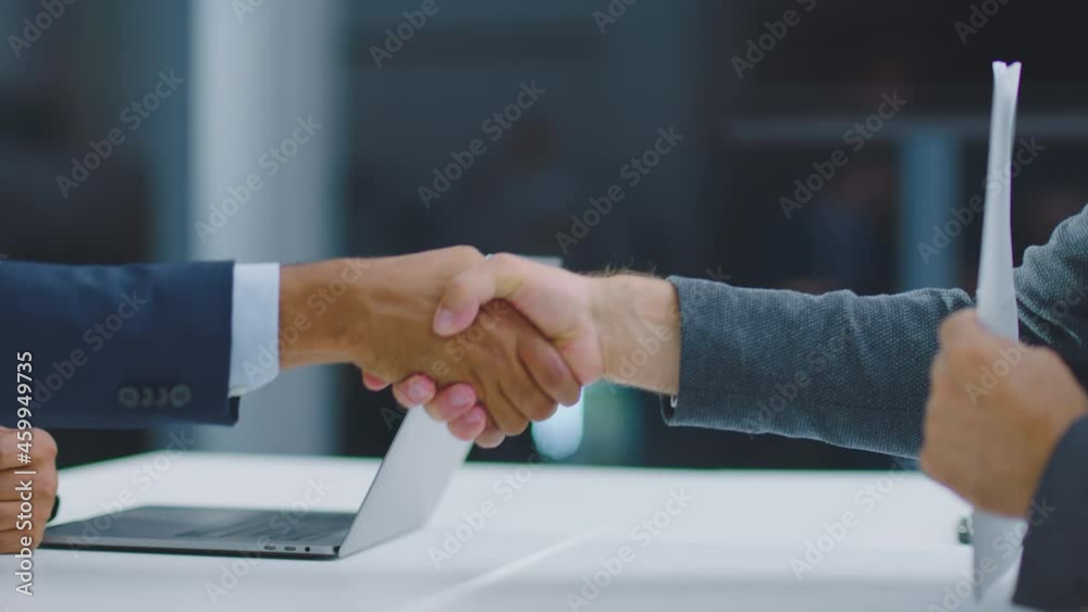 Slide and pan footage on handshaking above table in office. Making great deal. Modern open space office interior.