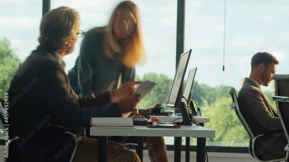 Panning timelapse footage of work collective in office. Large windows in background. Modern open space office interior.