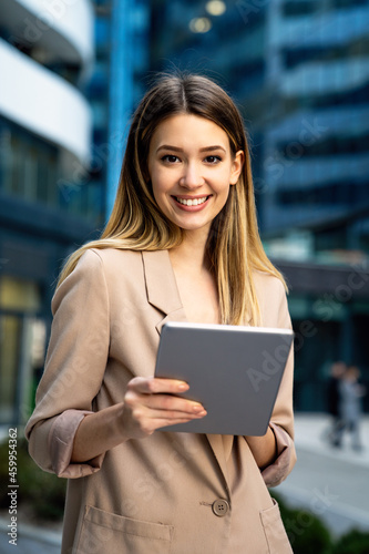 Successful businesswoman using a digital tablet while standing in front of business building.