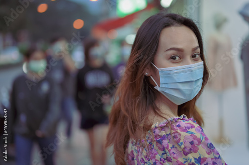 Young women wearing surgical protection mask looking back to camera when her walking onthe street