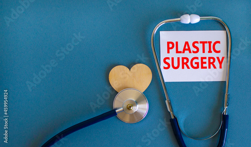 Plastic surgery symbol. White card with words Plastic surgery, beautiful blue background, wooden heart and stethoscope. Medical and plastic surgery concept.
