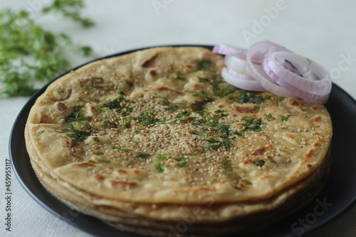 Perfectly round Paratha. Indian flatbread made of wheat flour topped with sesame seeds and coriander leaves photo