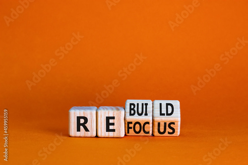 Refocus and rebuild symbol. Turned cubes and changed the word 'refocus' to 'rebuild'. Beautiful orange table, orange background. Business refocus and rebuild concept. Copy space.