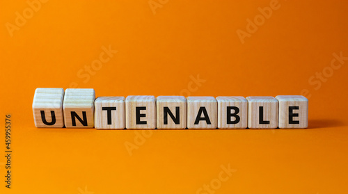 Tenable or untenable symbol. Turned wooden cubes and changed the word 'untenable' to 'tenable'. Beautiful orange table, orange background. Business, tenable or untenable concept, copy space. photo