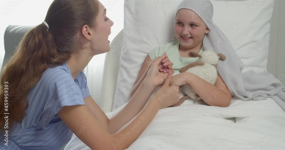 Woman visiting her daughter who is undergoing course of chemotherapy in clinic. Childhood cancer awareness concept
