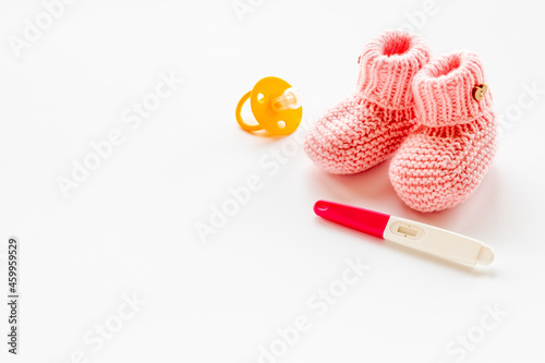 Pink baby girl booties with pregnancy test. Morherhood and pregnancy concept © 9dreamstudio