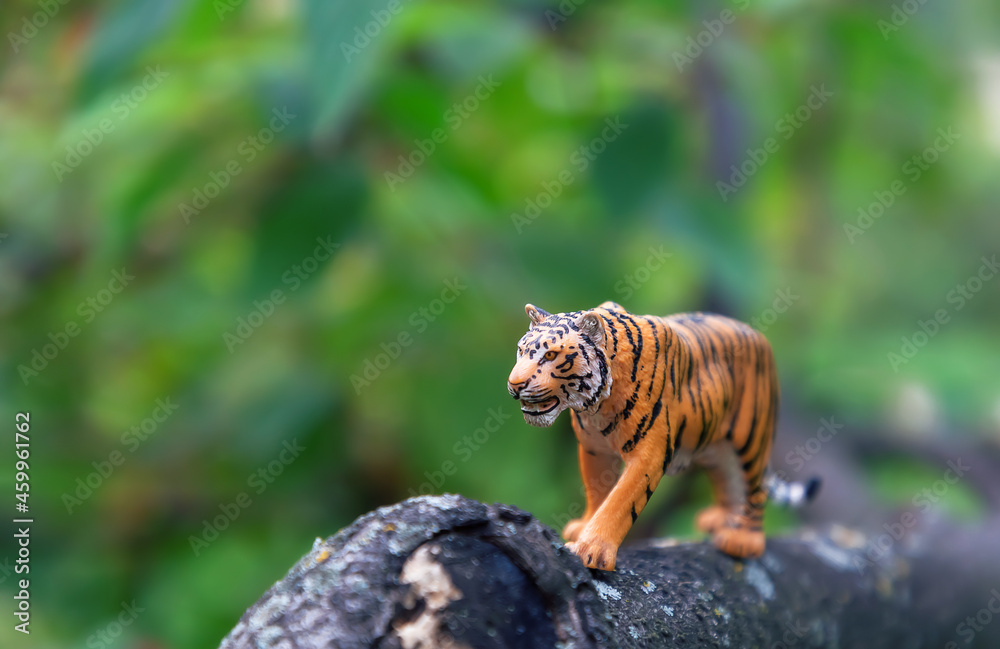Realistic plastic toy. A toy tiger in nature. Cute little animal toy for kids.