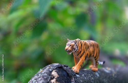 Realistic plastic toy. A toy tiger in nature. Cute little animal toy for kids.