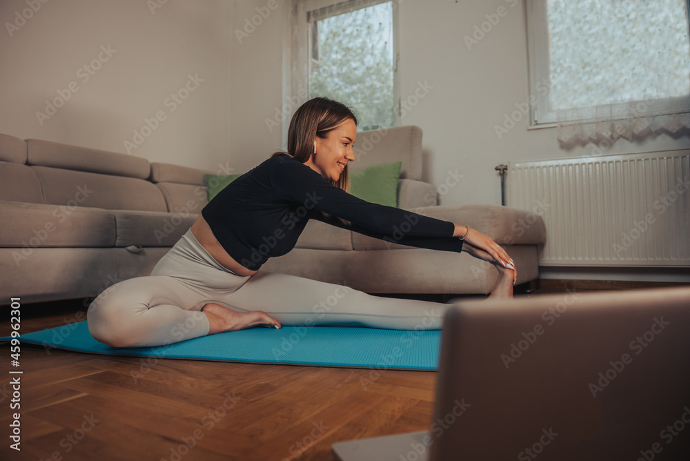 Woman stretching while training and doing her fitness routine at home