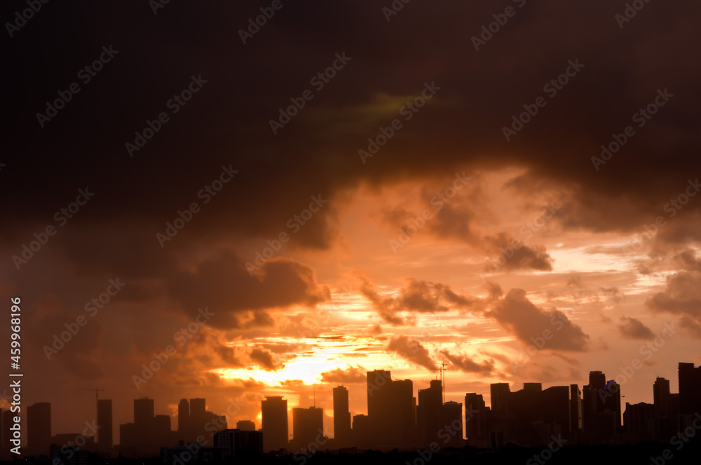 front view, very far distance of a silhouette of Miami skyline at dawn with clouds providing golden sky, with powerful light
