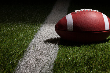Low angle view of a football at a yard line with dramatic lighting