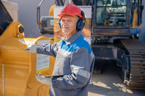 Engineer man in helmet with digital remote control tablet for automation of production at open coal mine.