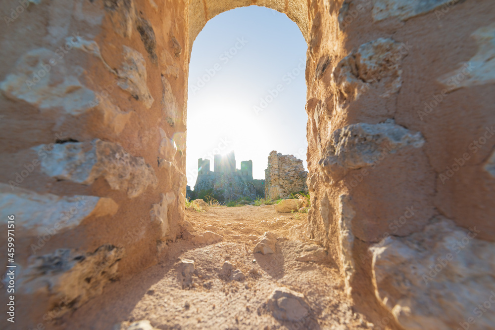 Castle ruins on mountain top at Rocca Calascio, view through stone window, landmark in the Gran Sasso National Park, Abruzzo, Italy. Clear blue sky sun burst in backlight