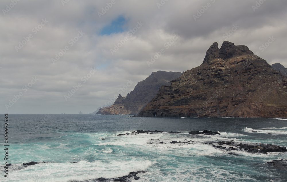 large pebble mountain by the calm sea in an arid environment of the canary islands under cloudy skies