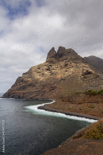 large pebble mountain by the calm sea in an arid environment of the canary islands under cloudy skies