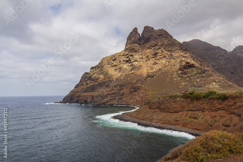 large pebble mountain by the calm sea in an arid environment of the canary islands under cloudy skies