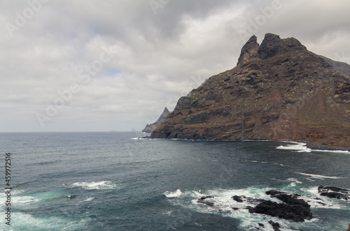 large pebble mountain by the calm sea in an arid environment of the canary islands under cloudy skies