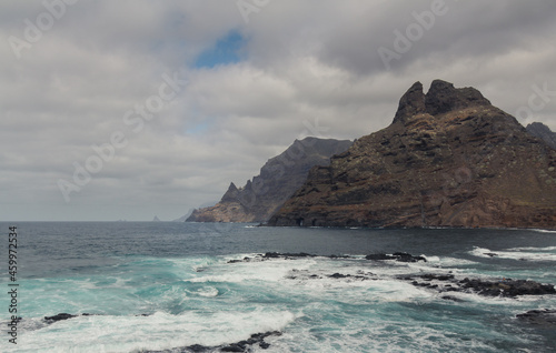 large pebble mountain by the calm sea in an arid environment of the canary islands under cloudy skies