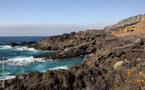 coast of the island of tenerife with large rock pools on a summer day under blue skies