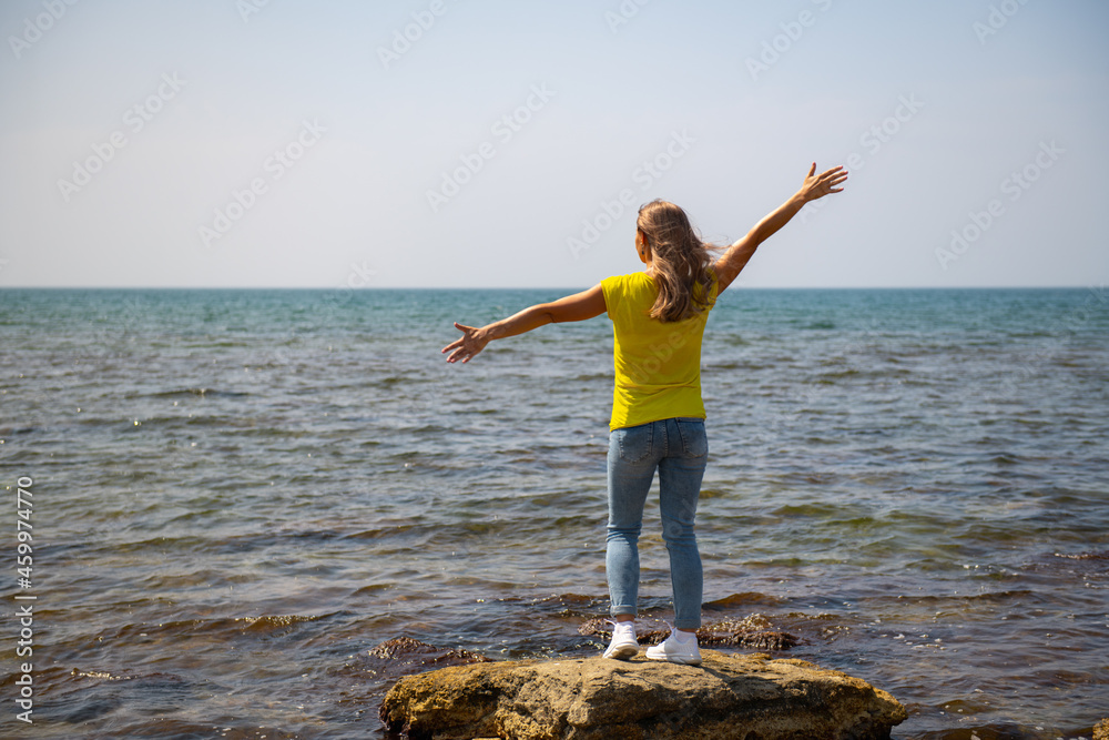 a woman in a yellow T-shirt stands on the shore of the Caspian Sea