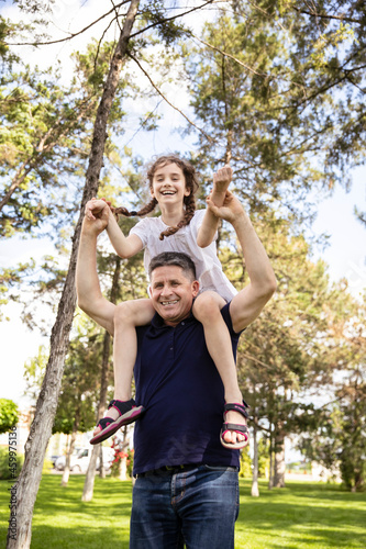 Grandfather holds his niece on his shoulders, he enjoys of a good day together in nature.