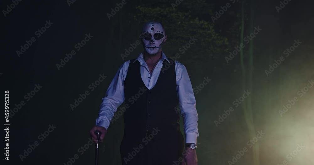 Spooky man with a make-up stick in a dark forest in a dead man's costume for Halloween Spooky man with a make-up stick in a dark forest in a dead man's costume for Halloween