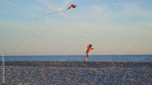 Happy Kid runs with kites along the sea line. children playing with a kite at sea. family vacation concept with children at sea