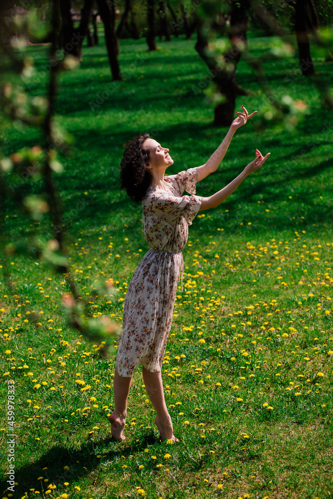 Young attractive woman with curly long hair posing in spring blooming garden, apple trees Young attractive woman with curly long hair posing in spring blooming garden, apple trees